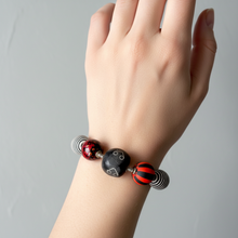 Load image into Gallery viewer, red, black and white bracelet on an arm with a grey background.