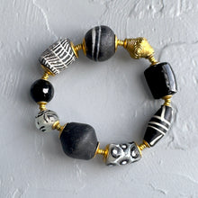 Load image into Gallery viewer, Bracelet with black, gold, and patterned beads on a light gray background