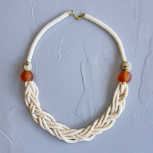Load image into Gallery viewer, cream Necklace with braided design and dark orange beads on a gray background