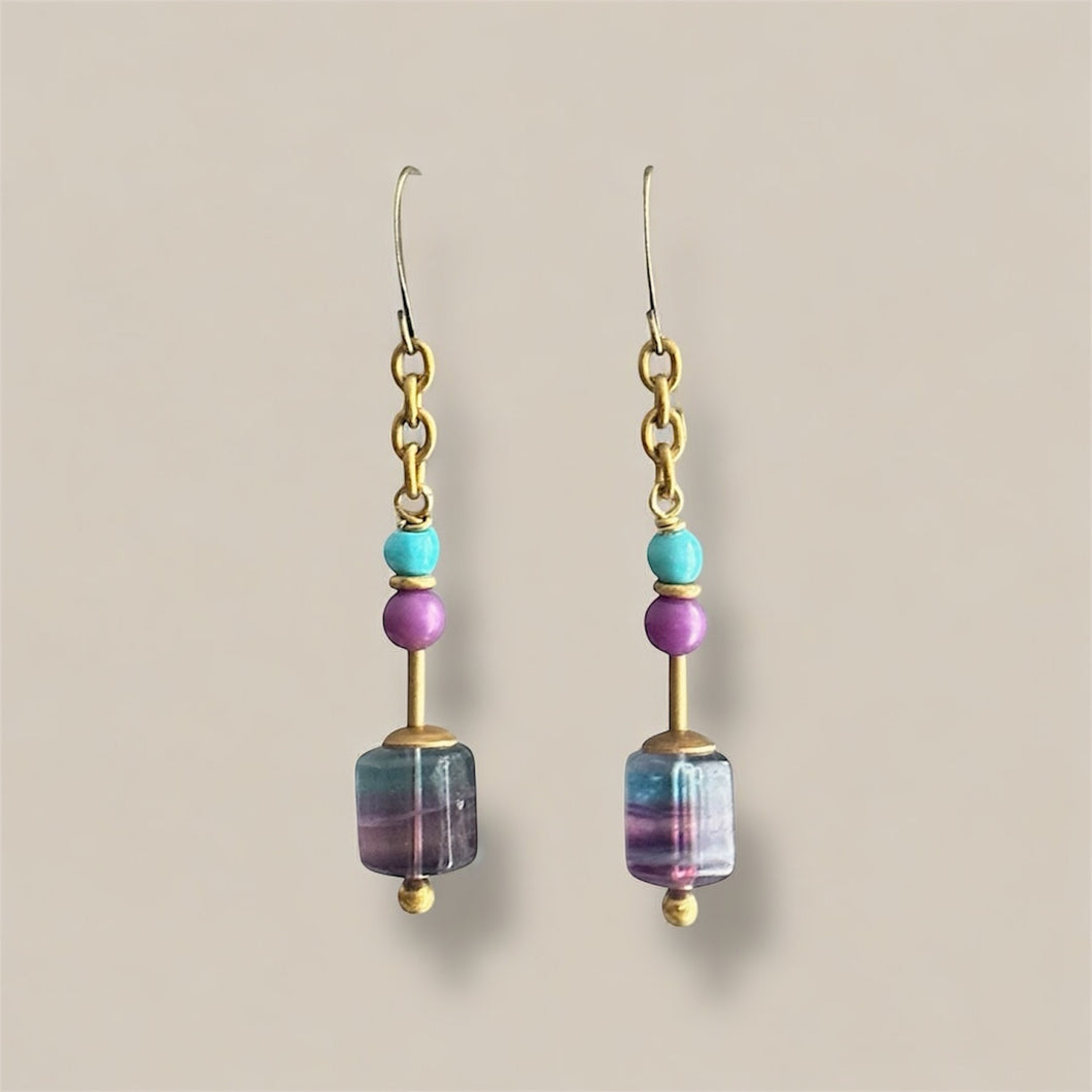Pair of earrings with turquoise, lavender and pool blue beads on a beige background