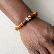 Load image into Gallery viewer, Bracelet with orange and brown beads on a wrist against a neutral background